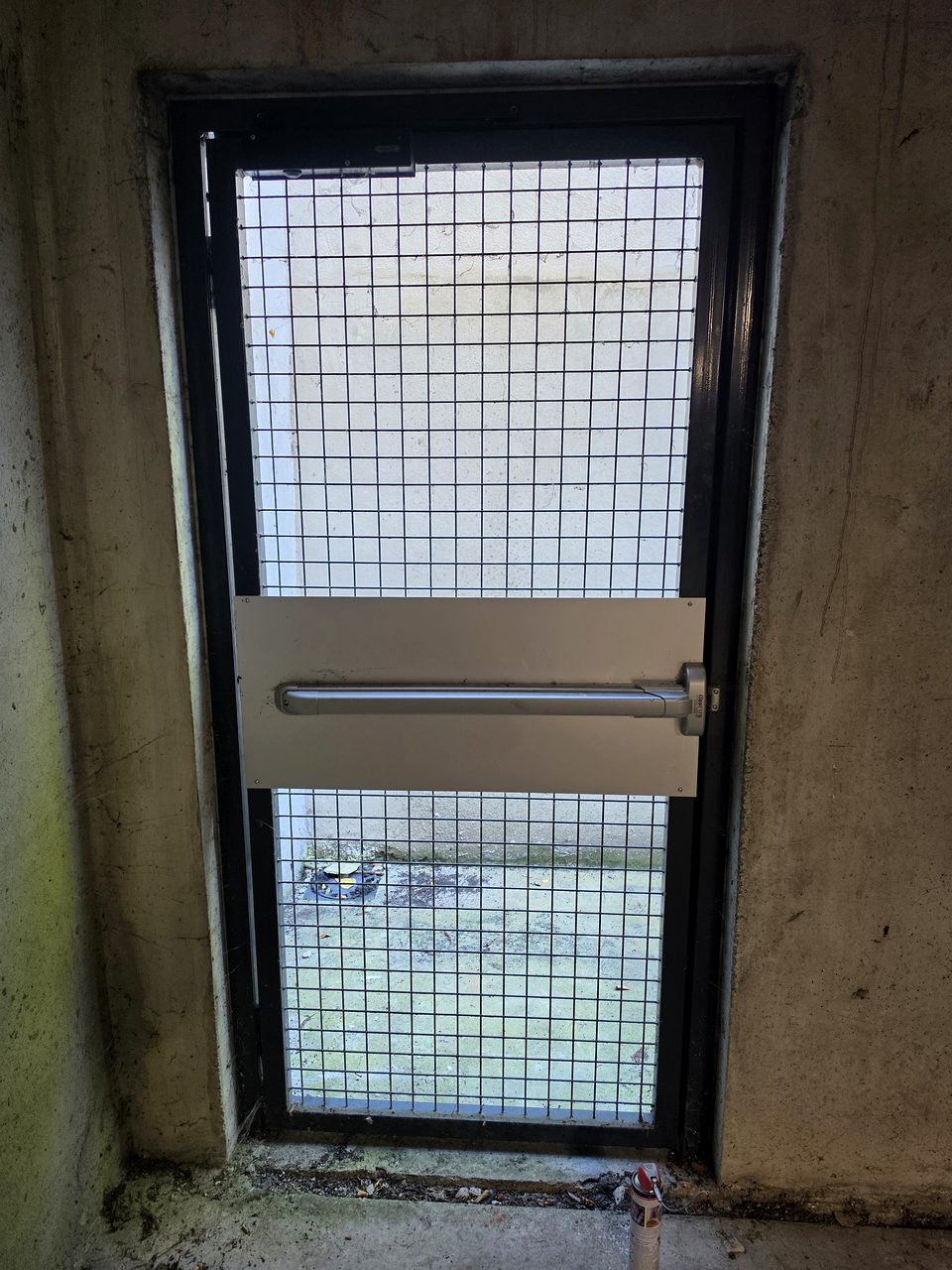 Portillon piéton grillagé de sous-sol avec barre anti-panique, avant réglage par un serrurier à Haubourdin